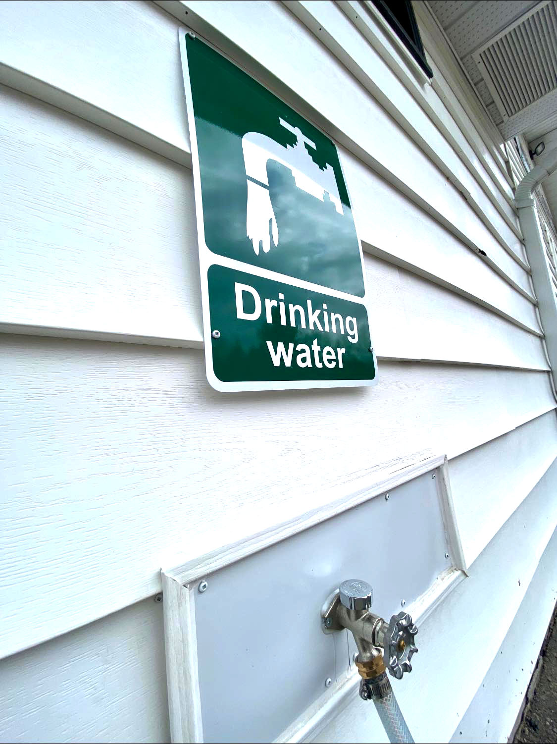 Image shows a tap with sign above that reads 'drinking water.'