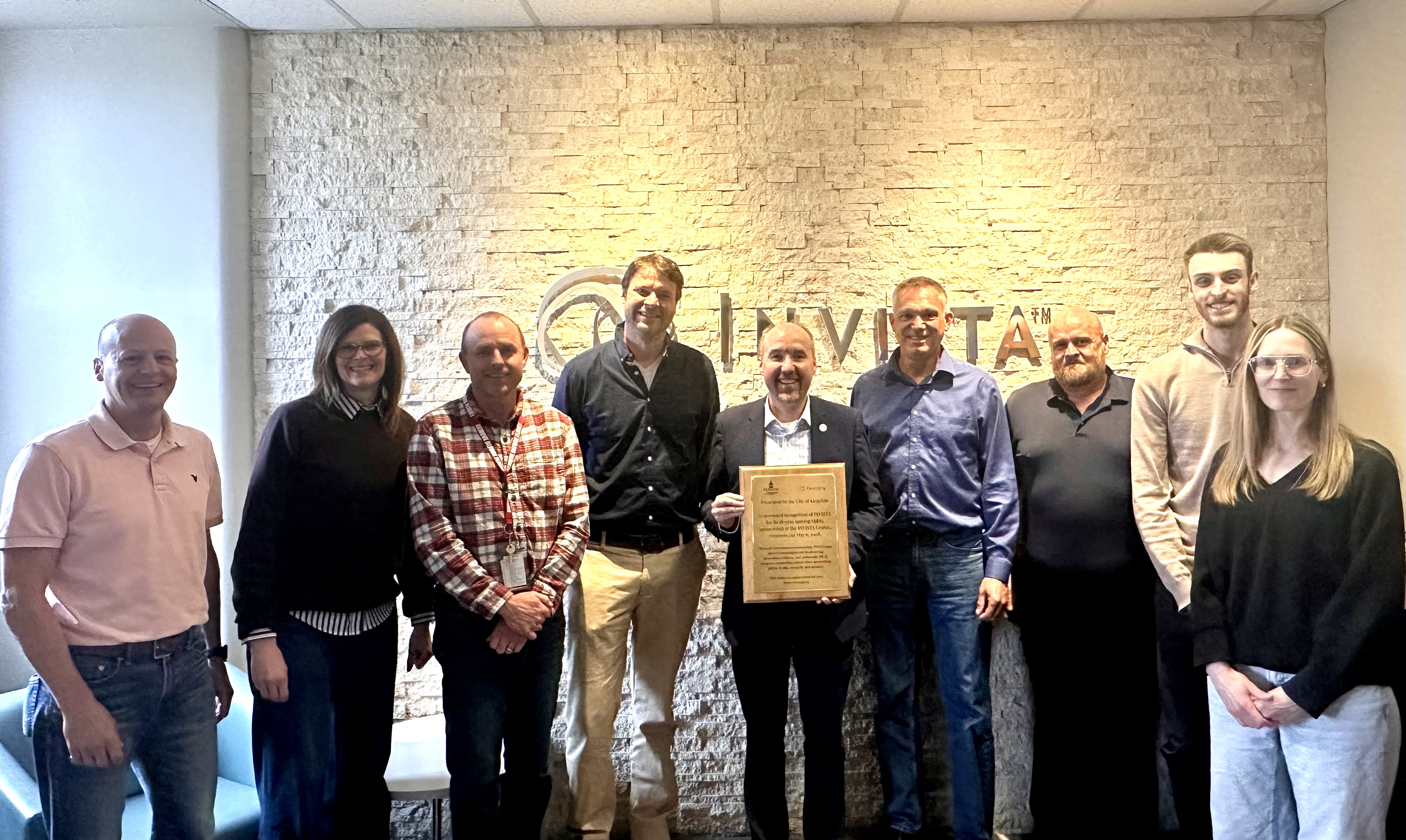 Mayor Paterson standing with INVISTA leadership team standing in front of a grey brick wall with INVISTA's logo.