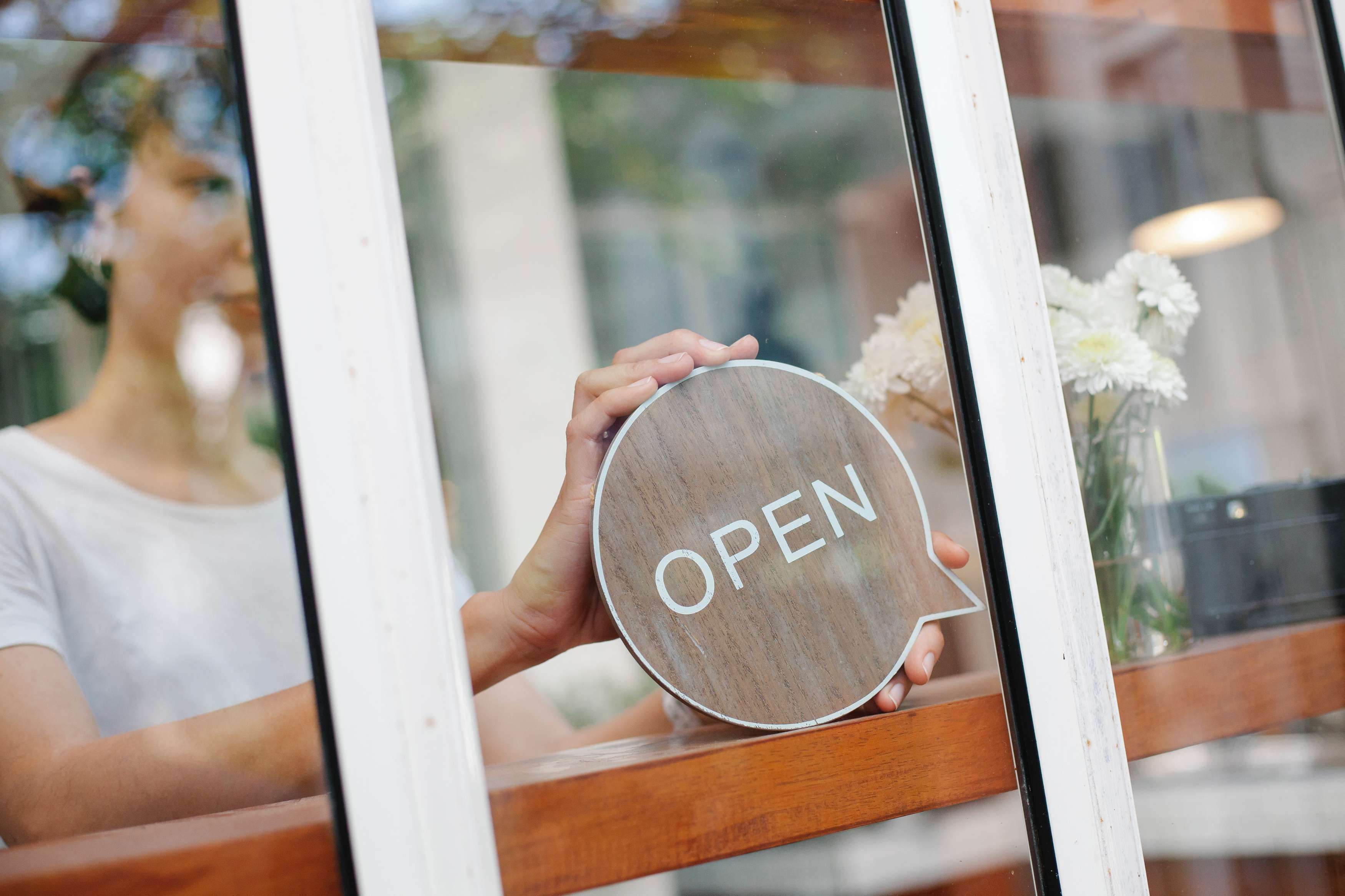 Open sign being placed in a storefront window.