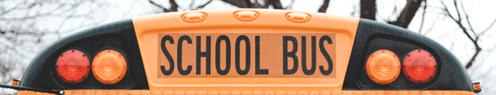 School bus viewed from the rear, showing the “SCHOOL BUS” sign and flashing warning lights.