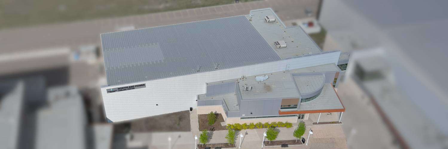 Aerial view of Northland Power Curling Centre in summer, with a blurred surrounding area.
