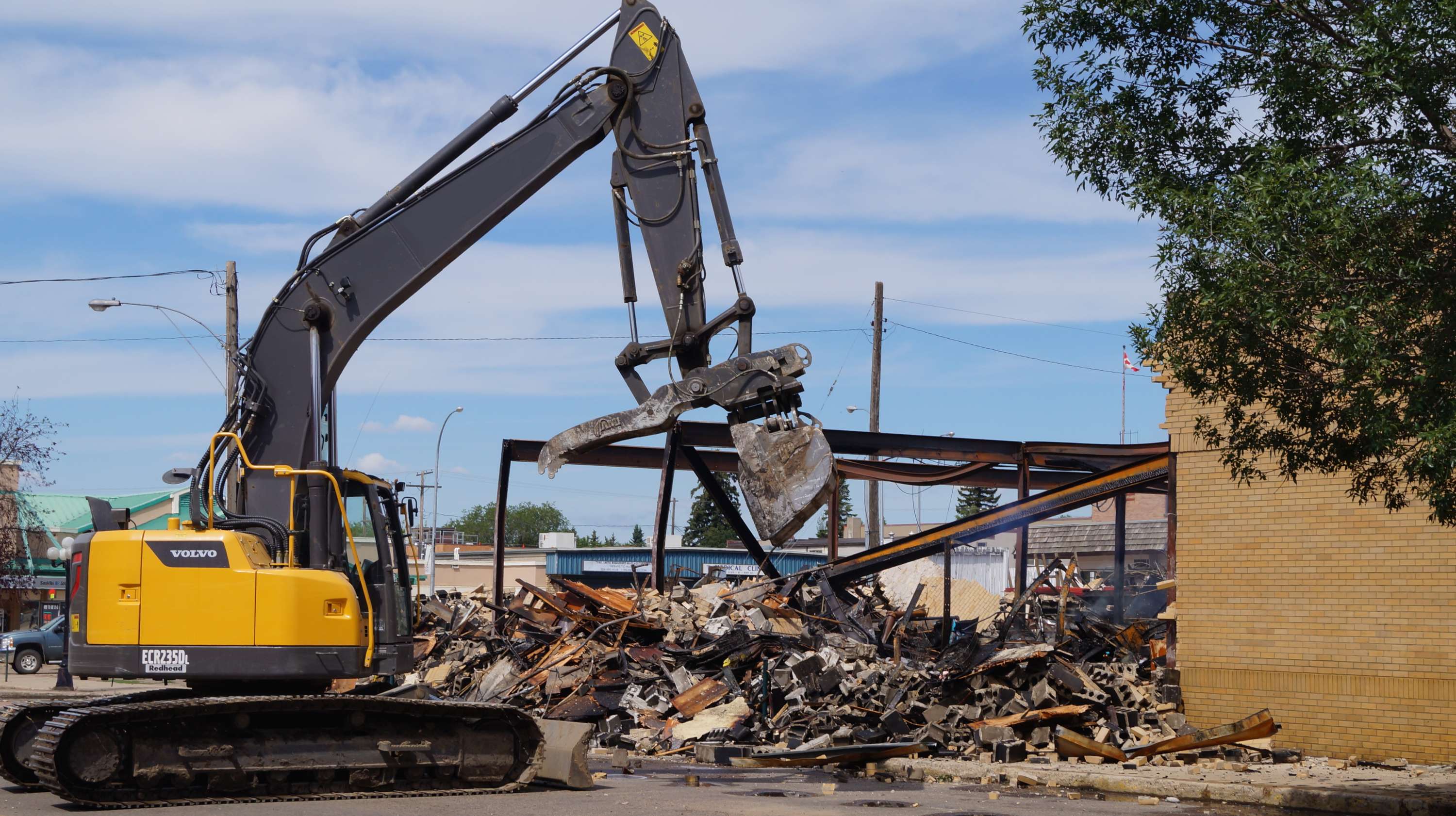 Excavator demolishing a building and sorting debris at a demolition site.