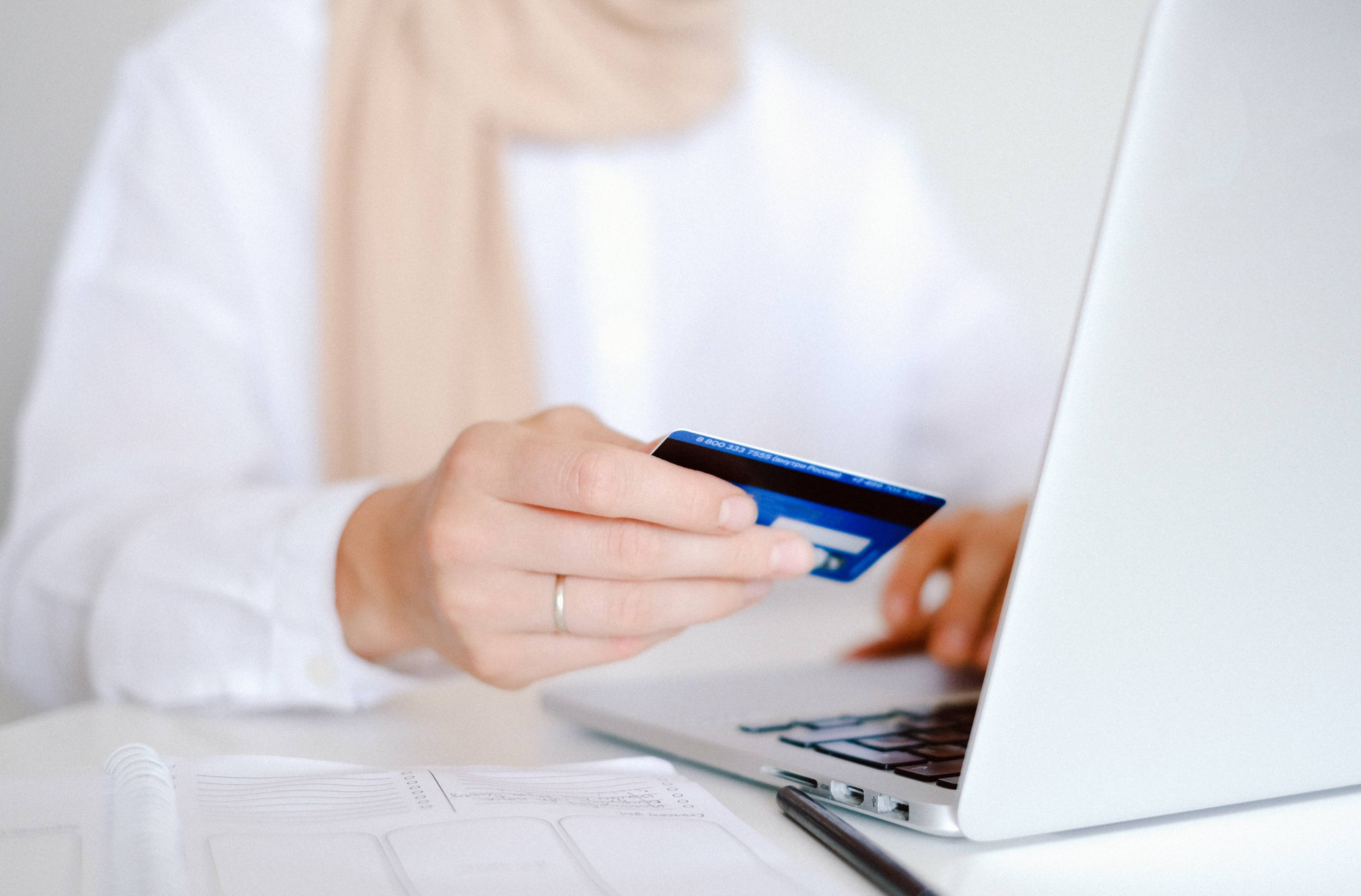 Person using a credit card while shopping online on a laptop.