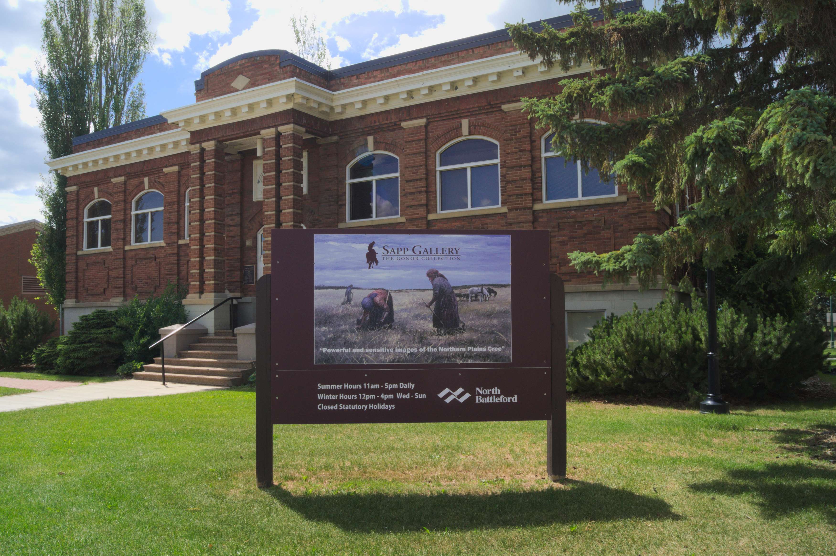 Allen Sapp Gallery building in summer, showcasing a sign with artwork and visitor information.