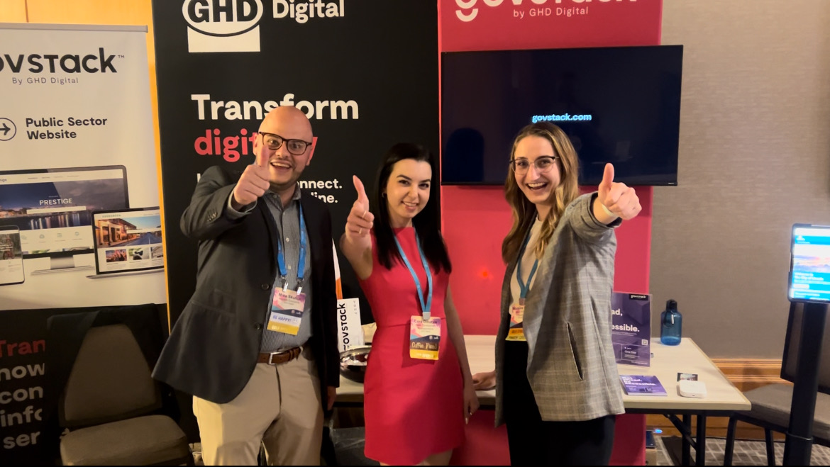 three people giving thumbs up standing in front of a booth.
