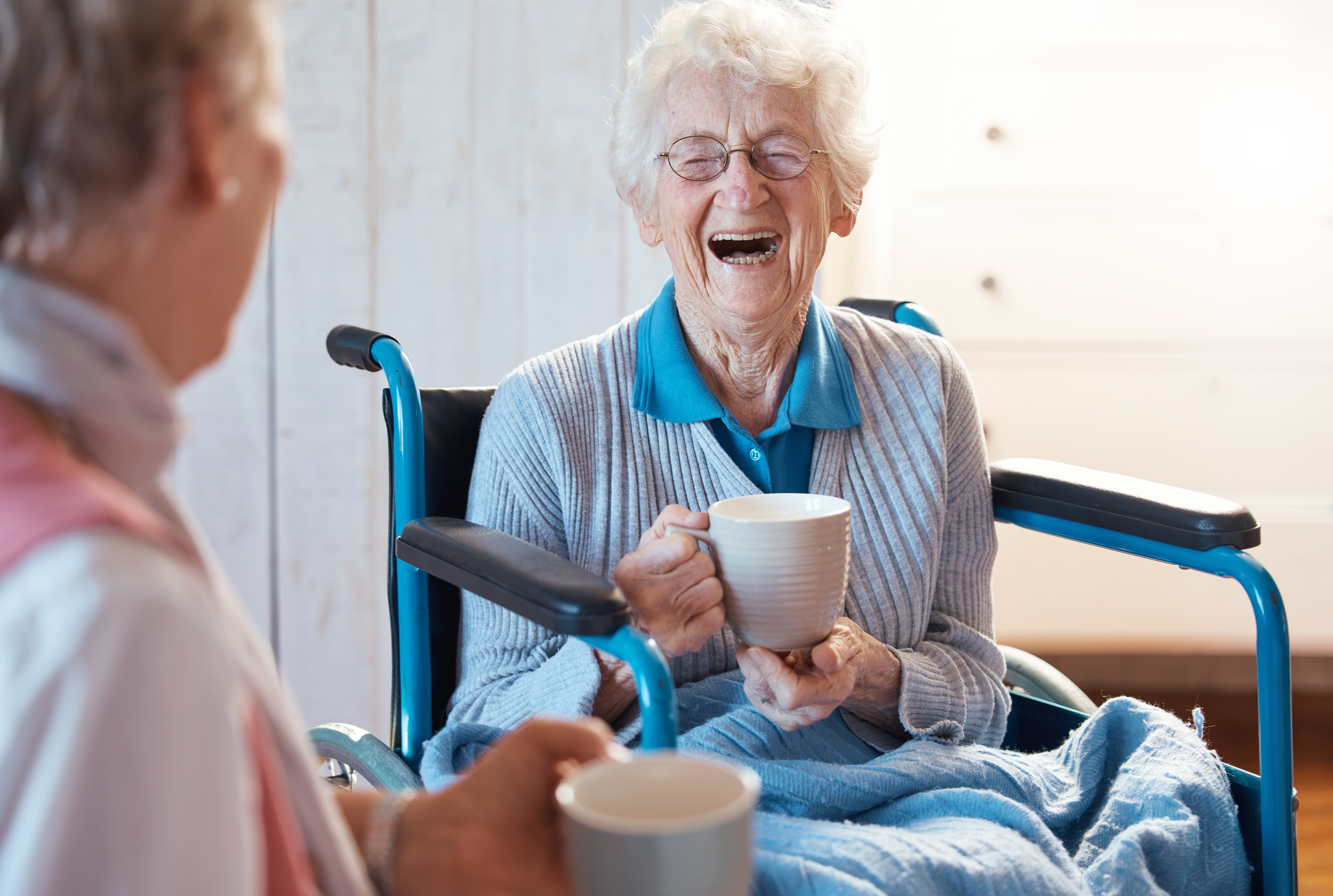 Older woman in a wheelchair laughing