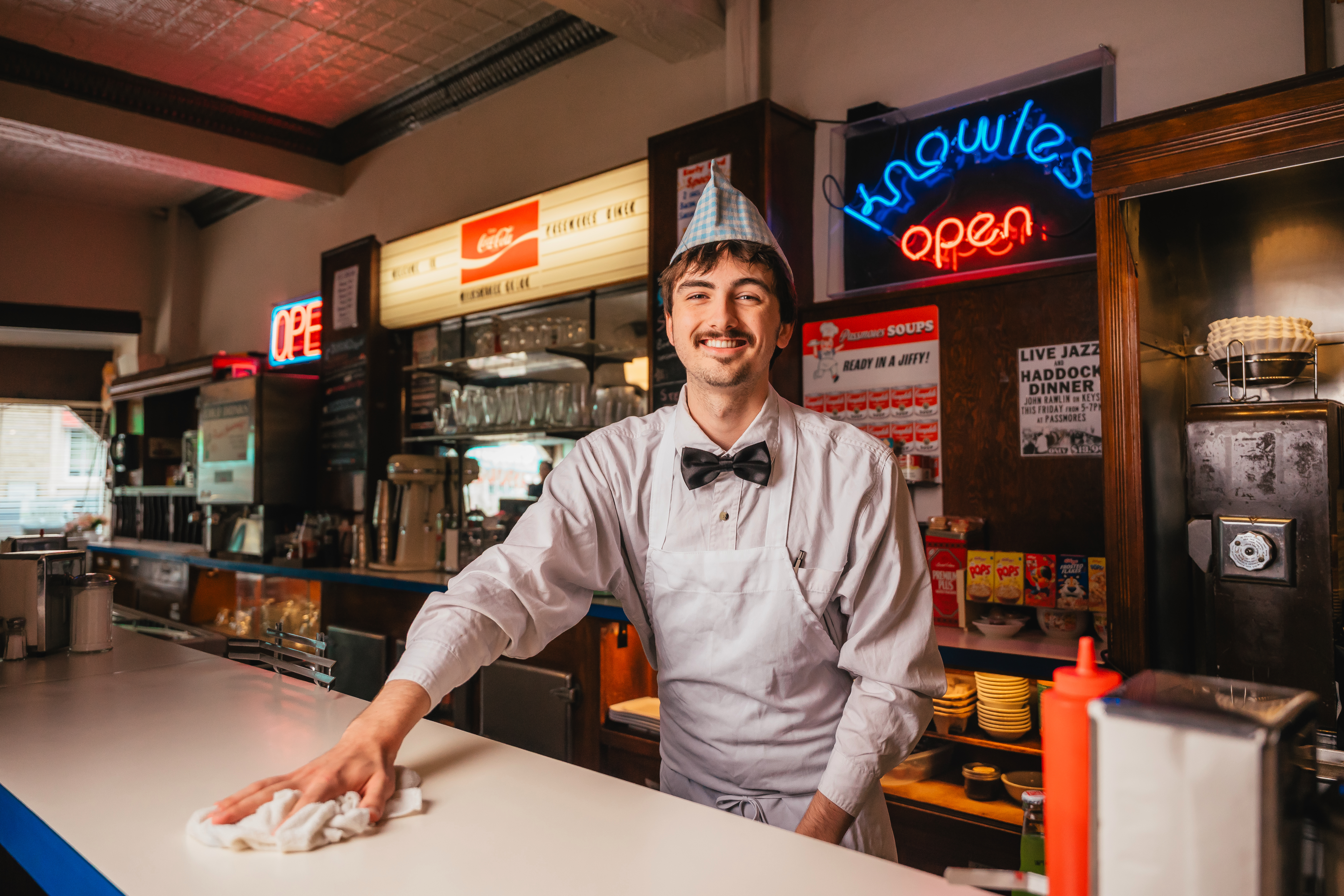 A man wipes down a countertop in a restaurant