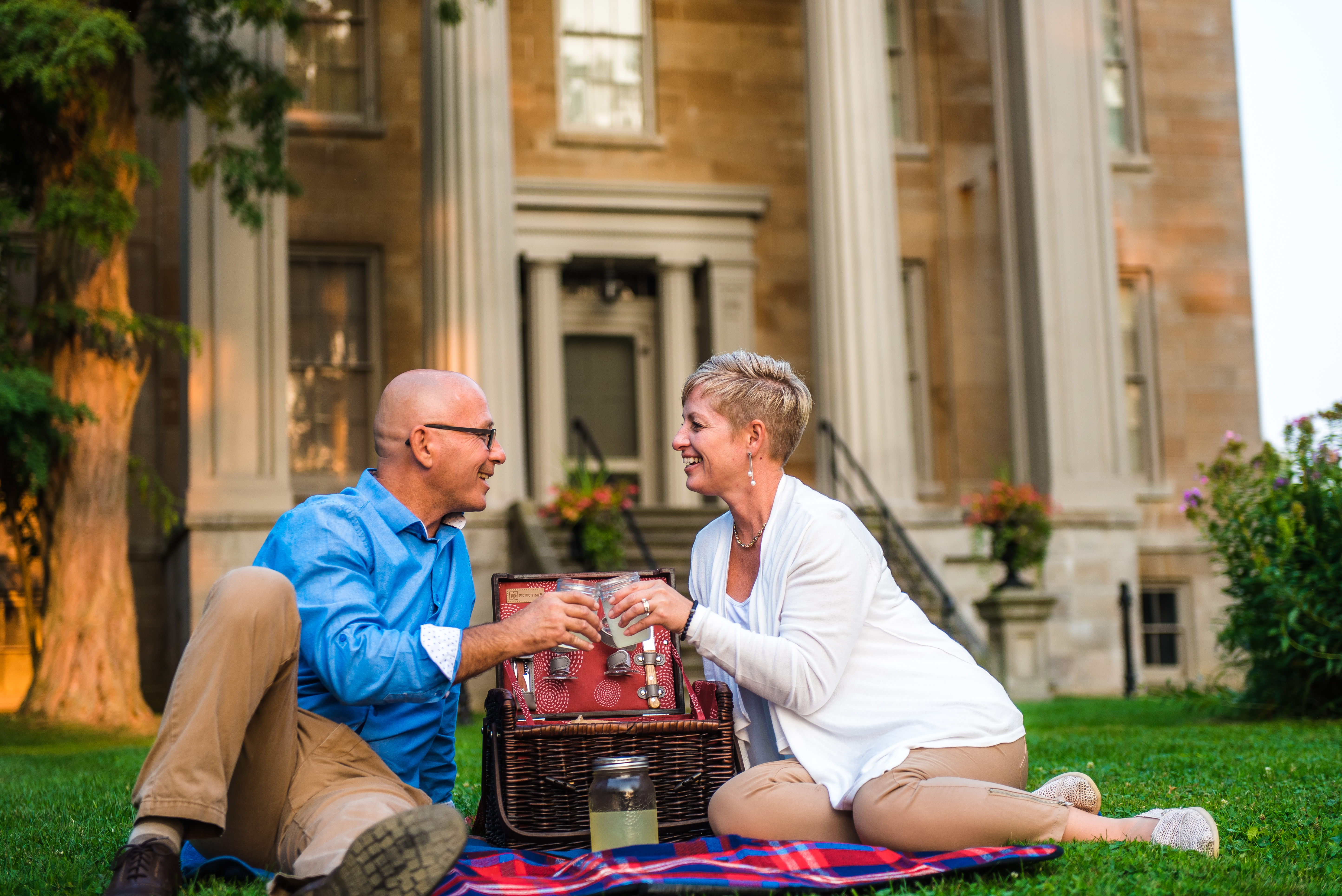 A man and woman share a toast over a picnic basket