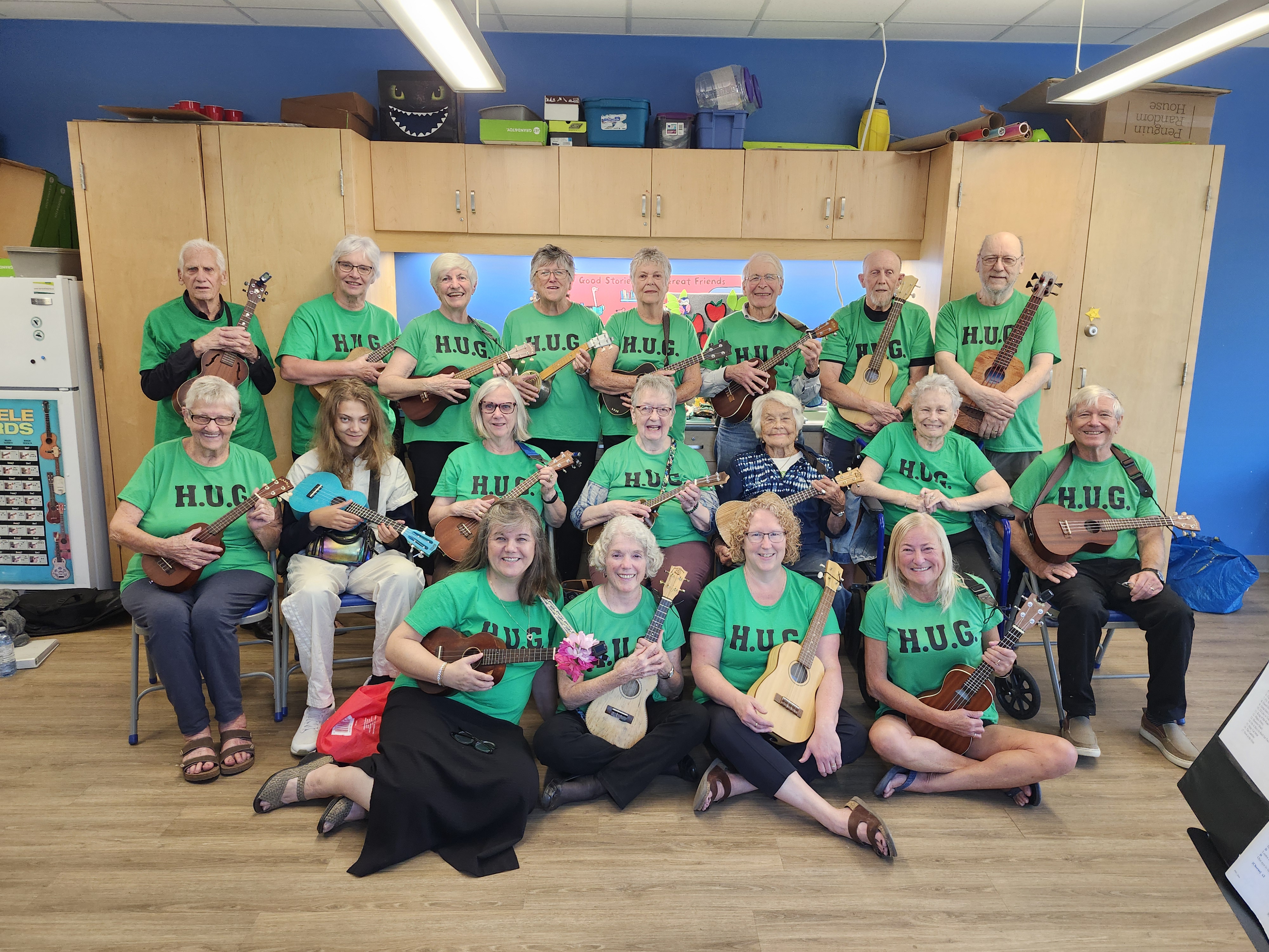 large group of adults holding ukuleles in matching green tshirts