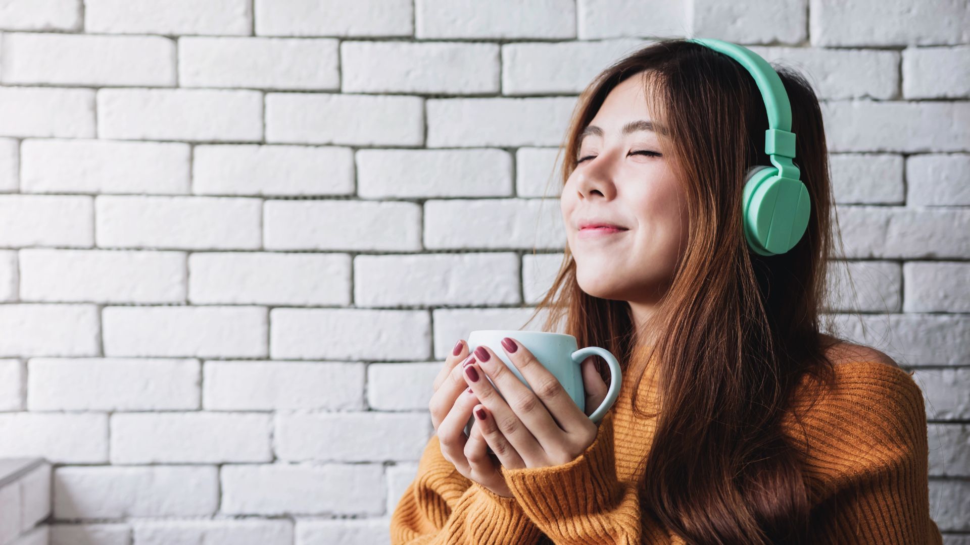 Woman Wearing Headphones With A Mug Of Coffee