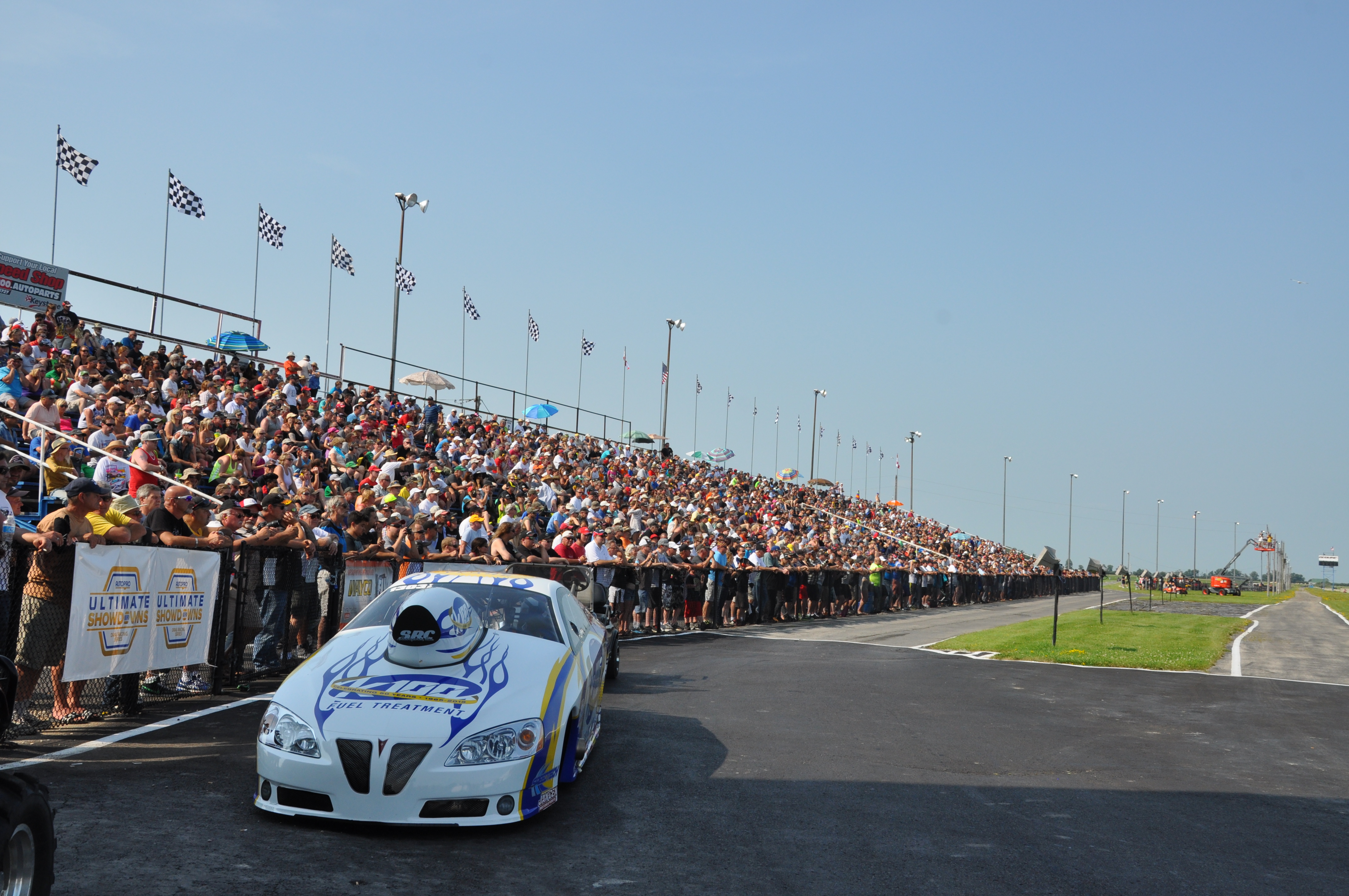 A race car sits in front of a large bandstand full of people