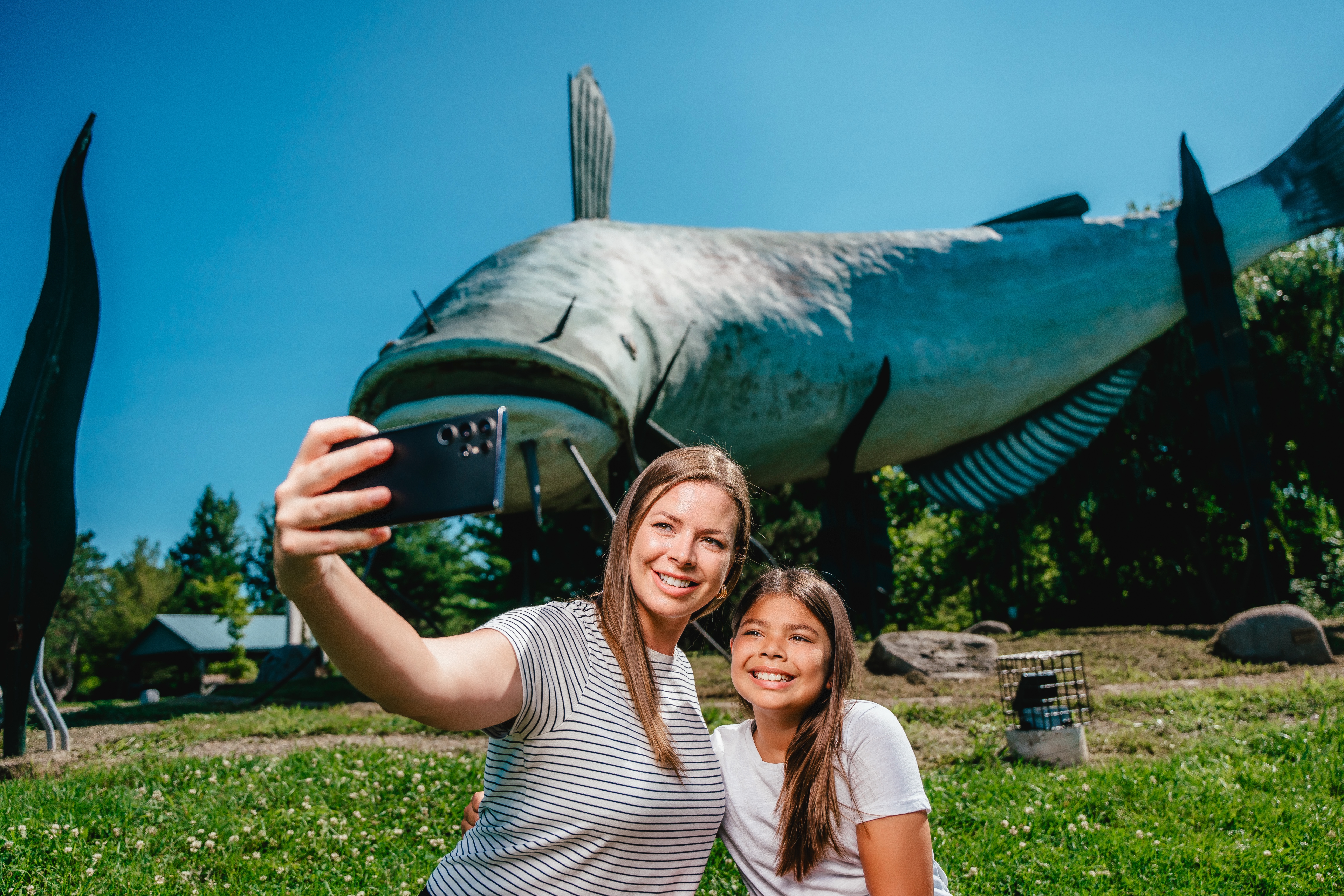 A mother and daughter taking a selfie in front of a mudcat statue