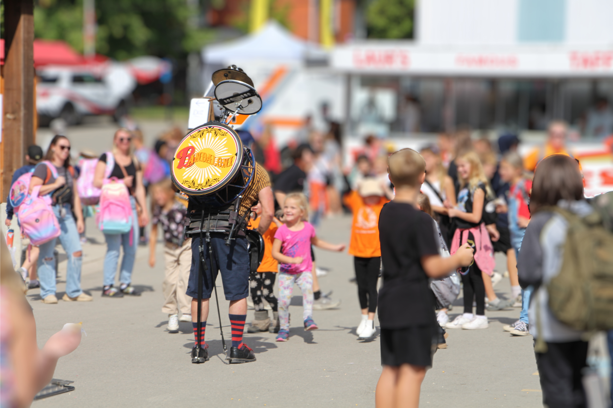 A one man band walks through a crowd at the fair