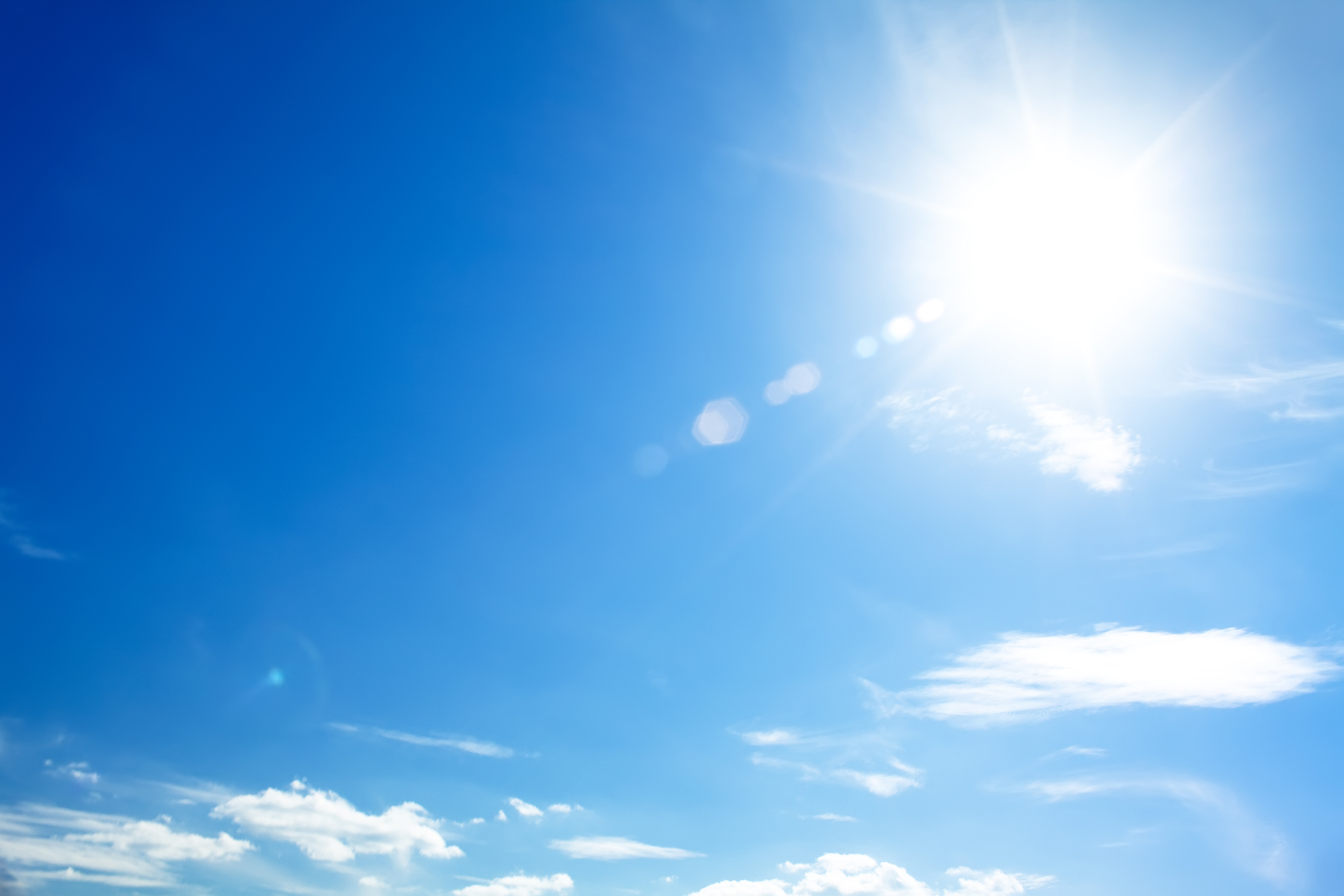 Sun and a few clouds against a blue sky