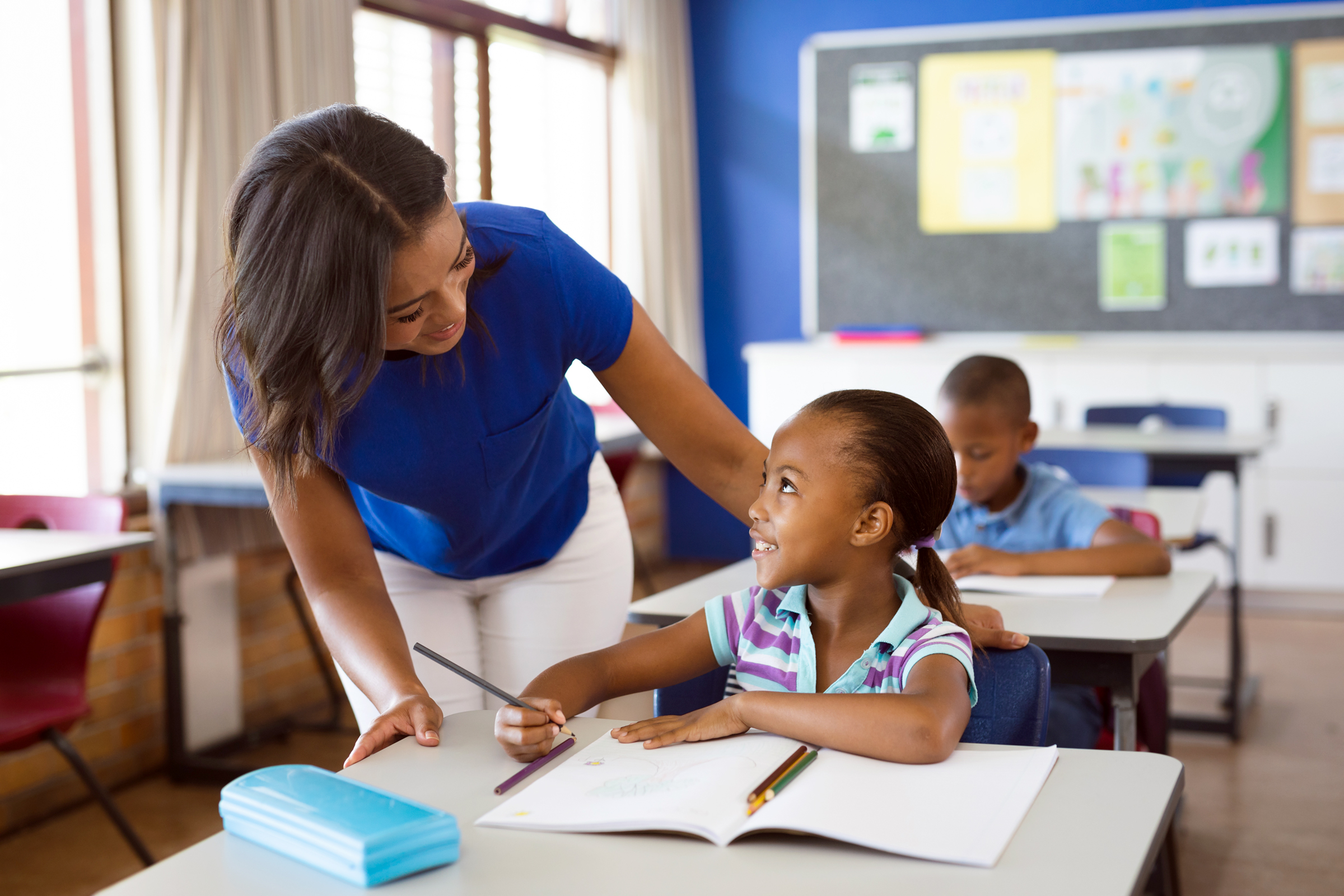 teacher assisting student at desk