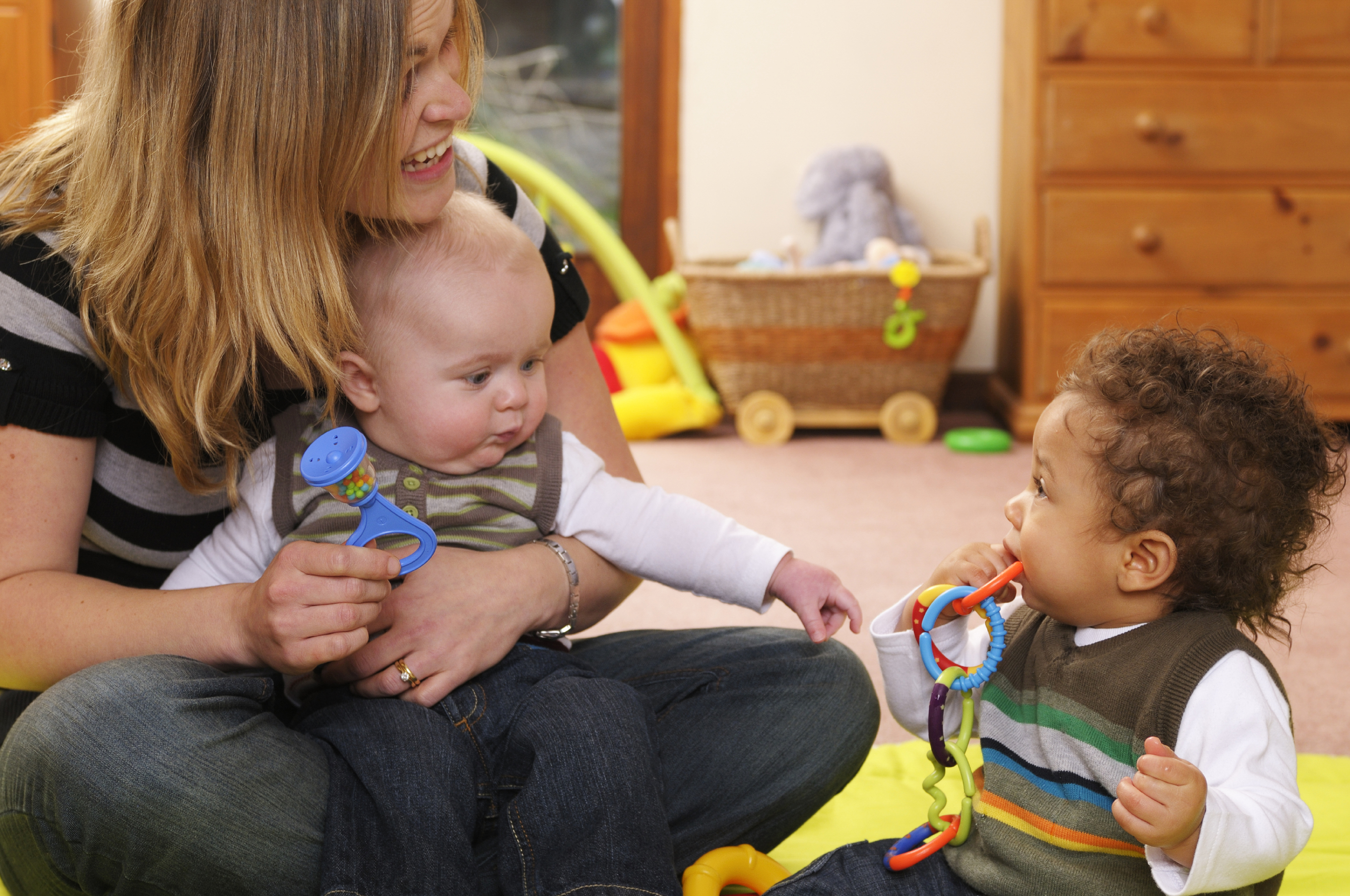 woman holding baby and toddler sitting on floor