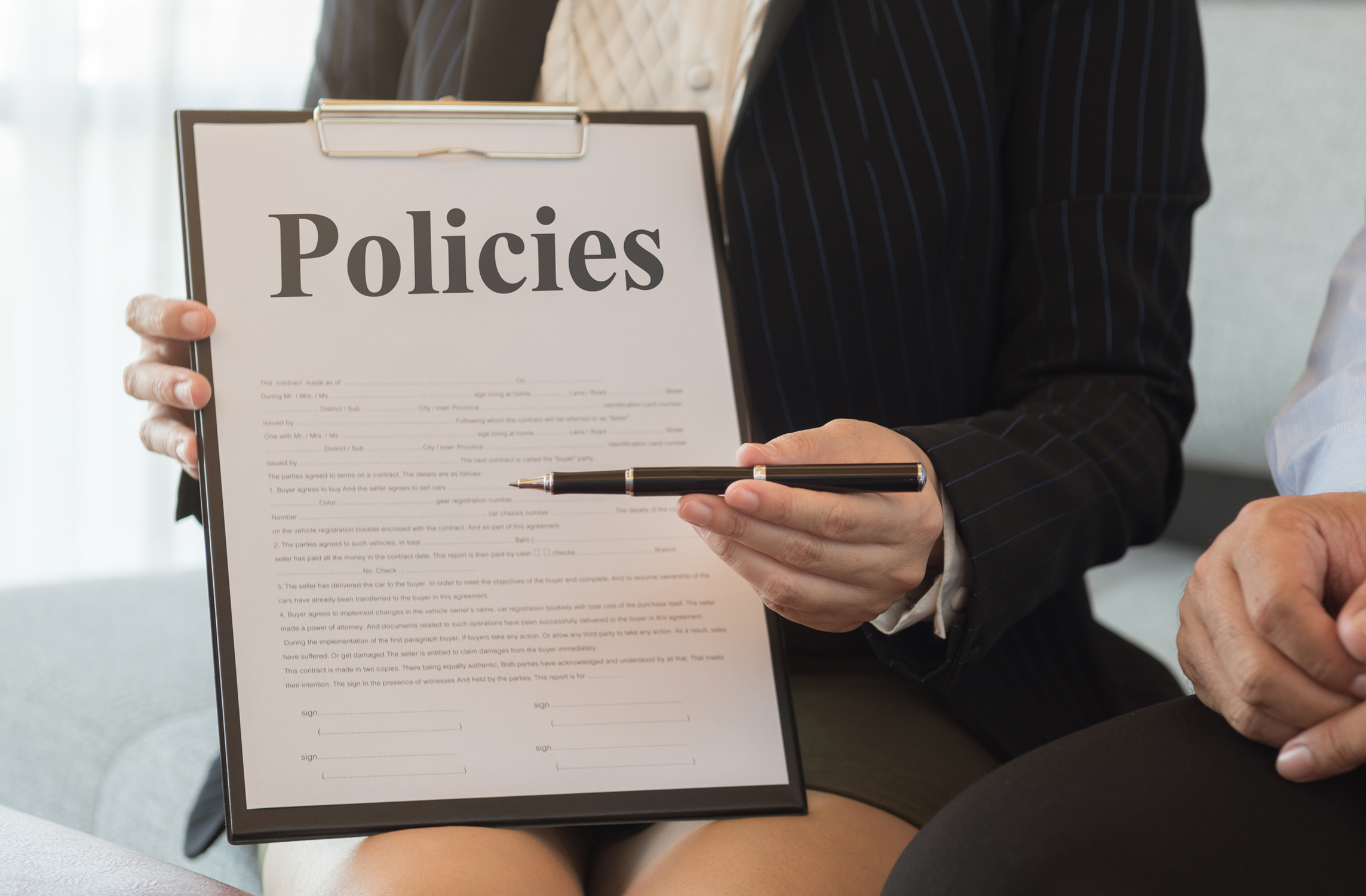 Person holding a clipboard that says "policies"