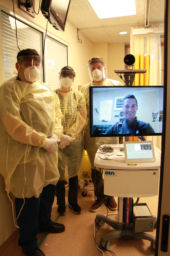 Three care providers standing beside virtual critical care system