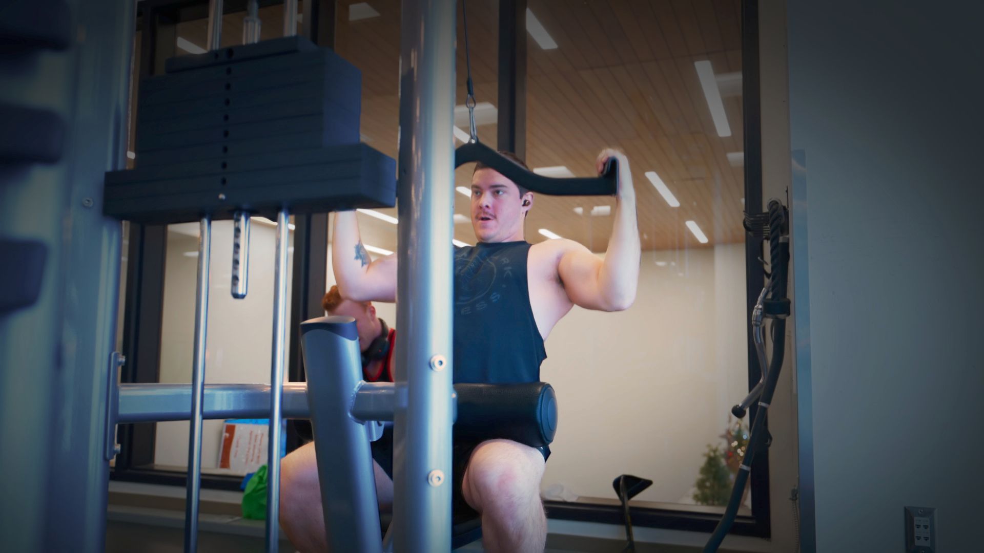 man working out pulling weights down while sitting on a workout bench