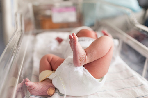 Baby lying in bassinette with Band-Aid on heel