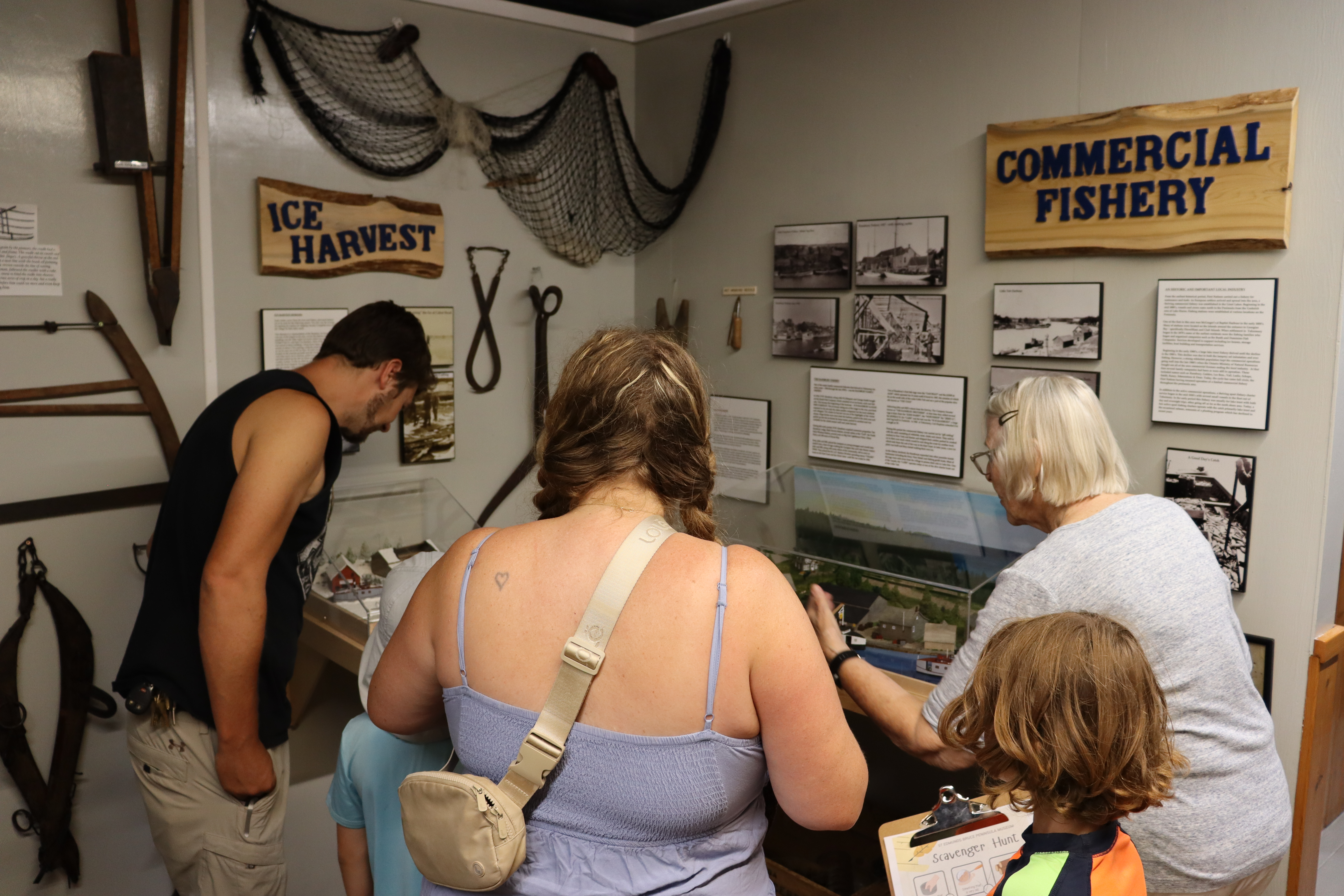 Close-up of a family participating in a hands-on learning activity indoors, with a volunteer guide present.