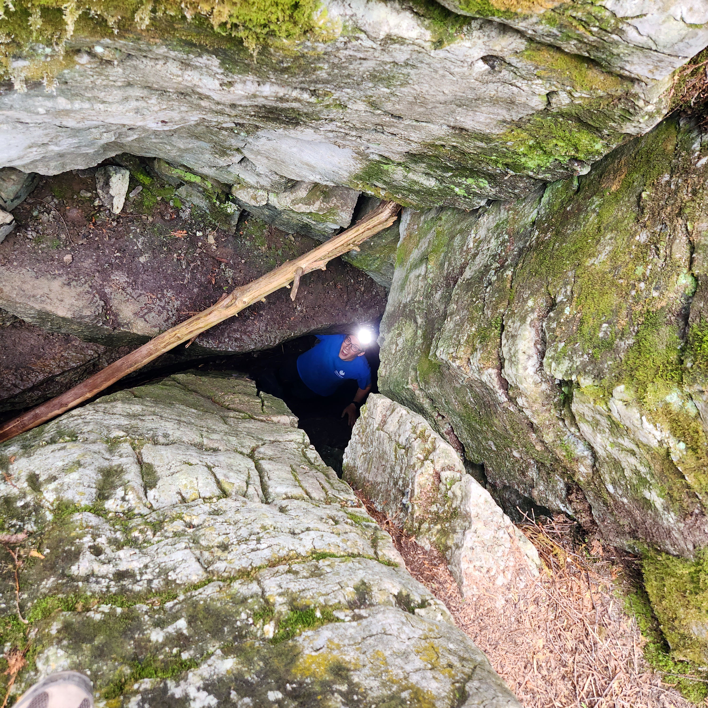 A spelunker wearing a headlamp looks up from inside a cave at Warsaw Caves Conservation Area