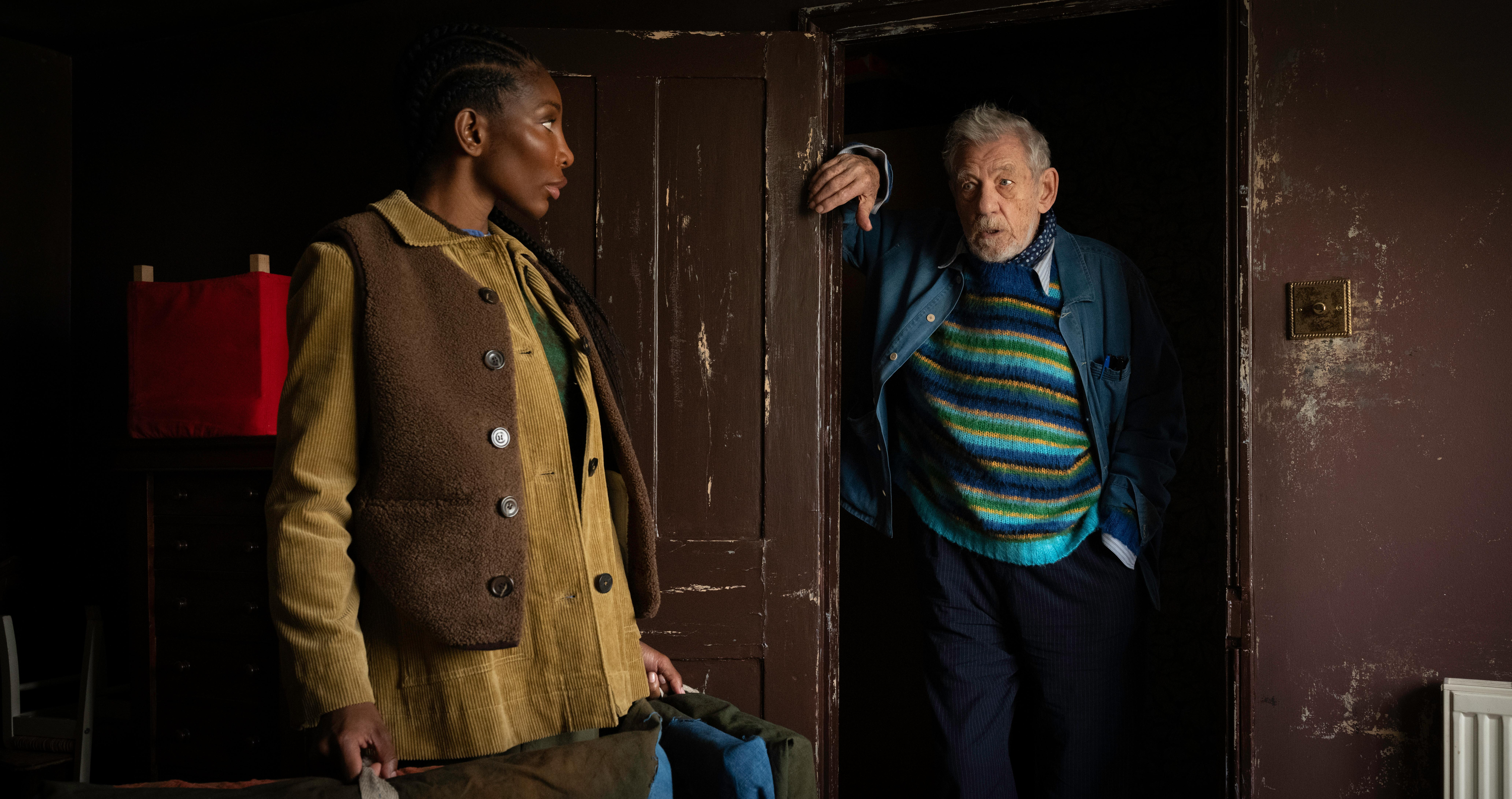 a young woman and an older man talk in a doorway