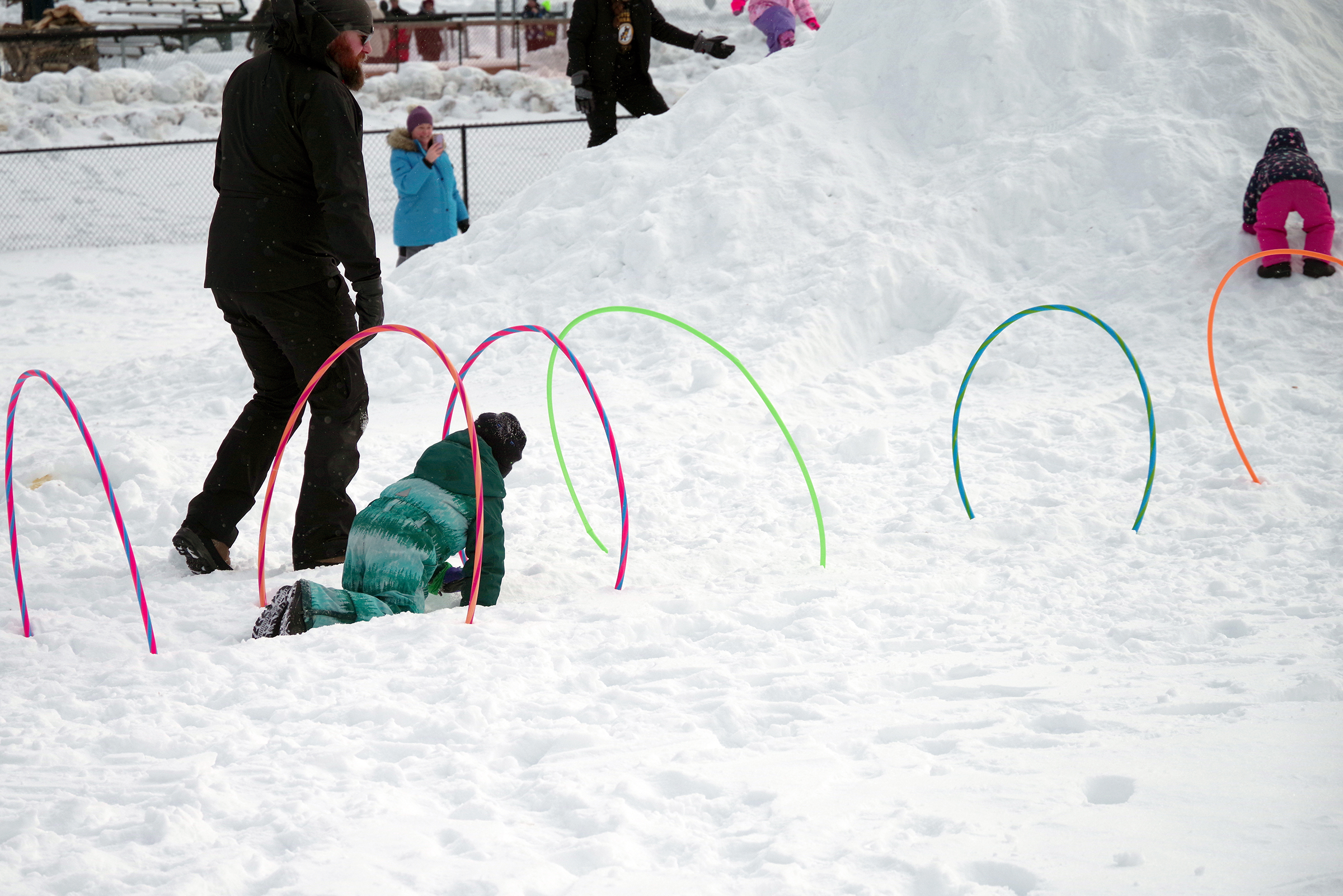 A child crawling through a hoop in the snow.